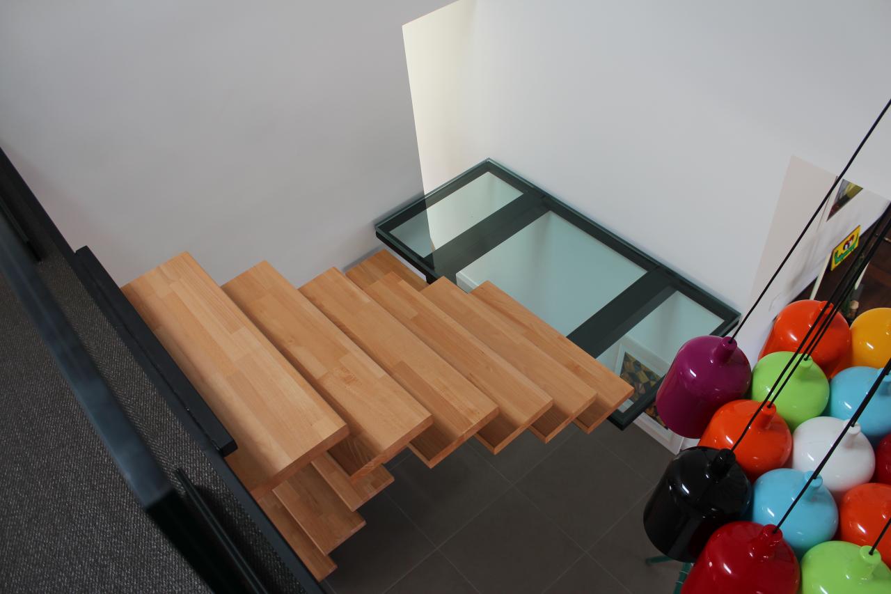 Escalier limon central en fer, marches en bois, palier en verre